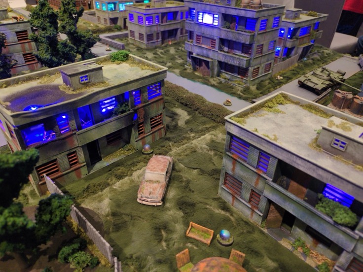 Tim dePertuis' stunning Zona Alfa table at KublaCon Prime 2026, with glowing buildings and scattered debris